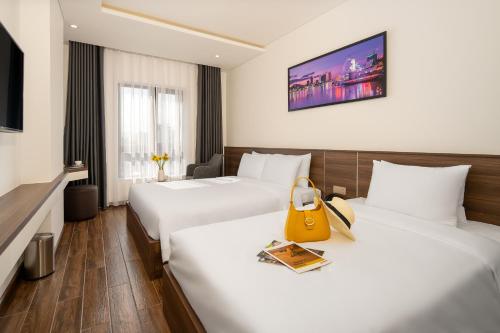 a hotel room with two beds and a yellow bag on the bed at Tan Phuong Nam Hotel & Apartment in Da Nang