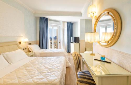 una camera d'albergo con due letti e uno specchio di Hotel Baia Imperiale a Rimini