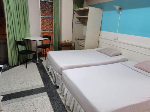 a hotel room with two beds and a table at Center Mansion at Hatyai in Hat Yai