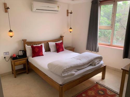 a bedroom with a bed with white sheets and red pillows at Moustache Agra in Agra