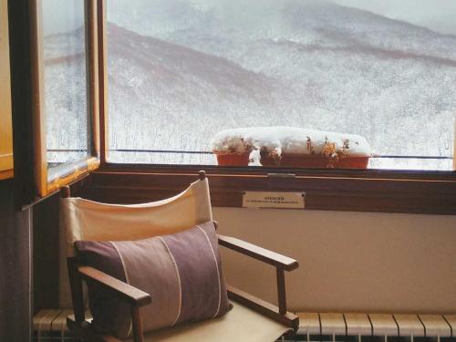 a chair sitting in front of a window with snow at Naquela Castroviejo in Castroviejo