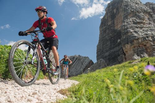 two people riding bikes on a mountain trail at Hotel Soreghes Gran Chalet in Campitello di Fassa