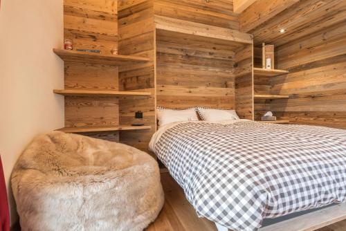 a bedroom with wooden walls and a bed and a chair at Majon Baticher in Canazei
