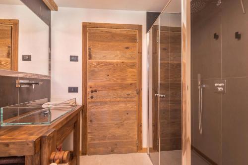 a bathroom with a shower and a wooden door at Majon Baticher in Canazei