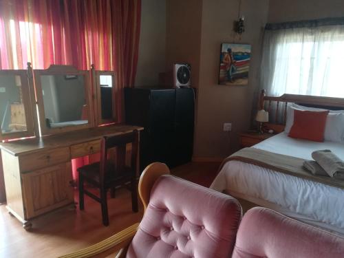 a bedroom with a bed and a desk with a television at Gaggle Inn Guest Lodge in Kroonstad