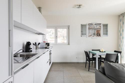 a kitchen with a sink and a table with chairs at Roggia Apartments by Quokka 360 - central flats with parking space in Lugano