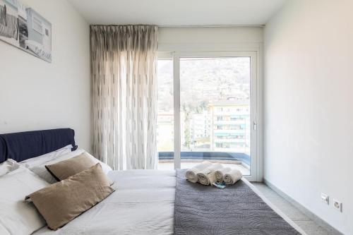 a bedroom with a bed and a large window at Roggia Apartments by Quokka 360 - central flats with parking space in Lugano