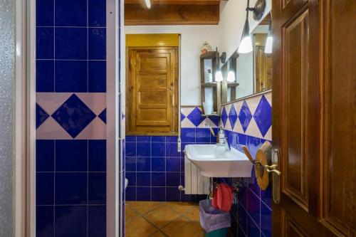 bagno con pareti piastrellate blu e lavandino di CASA ERNESTO Piscina Climatizada, porche y garaje a Zamora