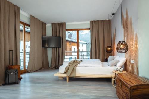a bedroom with a large white bed and a large window at Der Steinerwirt - hangout & hotel in Lofer