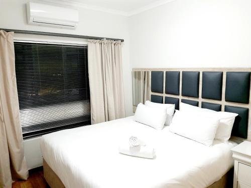 Un dormitorio con una gran cama blanca y una ventana en NST City Apartments @ Casalinga Villa en Nelspruit