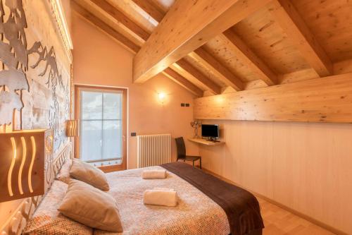 a bedroom with a large bed in a room with wooden ceilings at Zenith - Casa Azzurra Mansarda in Livigno