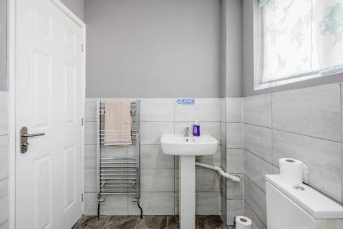 a white bathroom with a sink and a toilet at Remaj Serviced Accommodation, sleeps 7 & free parking in Laindon