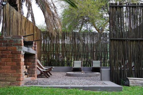 a backyard with a fire pit and two chairs and a fence at Thaba Pitsi Safari Lodge in Bela-Bela
