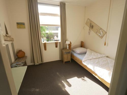 um pequeno quarto com uma cama e uma janela em De Jutter, in natuurgebied en vlakbij het Strand em Callantsoog