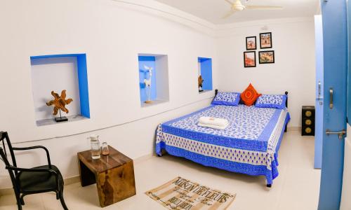 Dormitorio azul y blanco con cama y mesa en Aura B&B - The Haveli Homestay, en Jodhpur