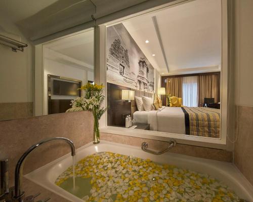 a bathroom with a bath tub with a bedroom at Hotel Royal Orchid Bangalore in Bengaluru