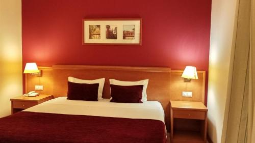 a hotel room with a bed with red walls at Hotel Monte Rio Aguieira in Almaça