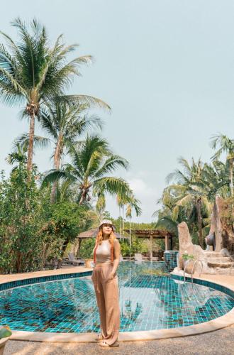 a woman standing in front of a swimming pool at The Spa Koh Chang Resort in Ko Chang
