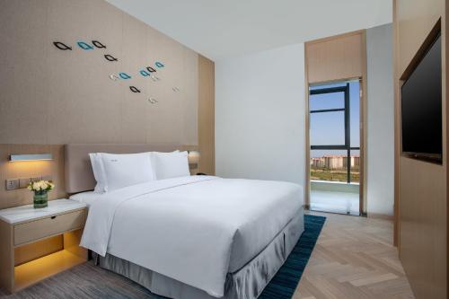 a bedroom with a large white bed and a large window at Holiday Inn Shanghai Dishui Lake by IHG in Nanhui