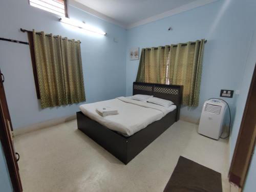a small bedroom with a bed and a fan at Kavitha House Homestay in Mysore