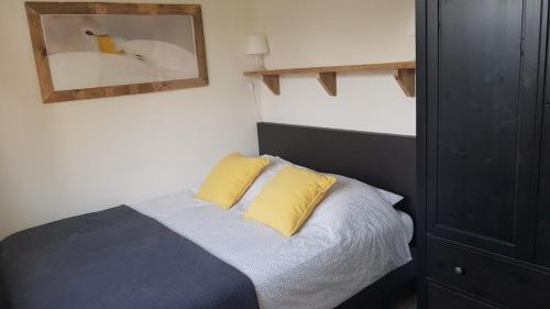 1 dormitorio con 1 cama con 2 almohadas amarillas en Mooi zo 1, en De Koog