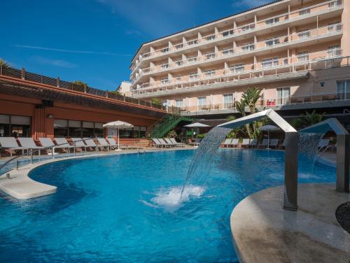 a swimming pool with a fountain in front of a hotel at Rosamar & Spa 4*s in Lloret de Mar