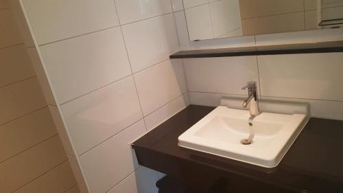 een badkamer met een witte wastafel en een spiegel bij Mooi zo 1 in De Koog