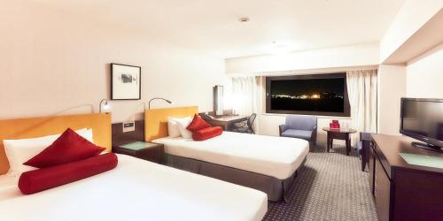 a hotel room with two beds and a flat screen tv at ANA Crowne Plaza Narita by IHG in Narita
