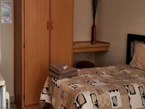 a bedroom with a bed and a wooden cabinet at Country Blue Luxury Guest House in Polokwane