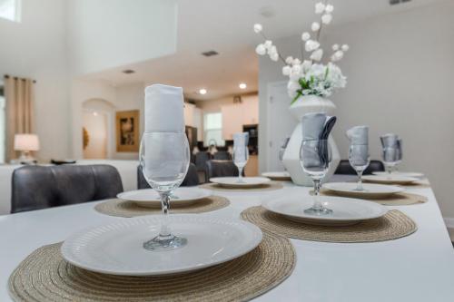 a table with plates and wine glasses on it at Villa wPrivate Pool &Themed Rooms, near Disney in Kissimmee