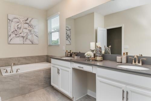 a bathroom with two sinks and a bath tub and a mirror at Villa wPrivate Pool &Themed Rooms, near Disney in Kissimmee