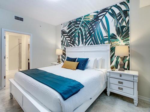 a bedroom with a white bed with a tropical wallpaper at Updated Condo, 5 mi to Disney, On-site Water Park in Kissimmee