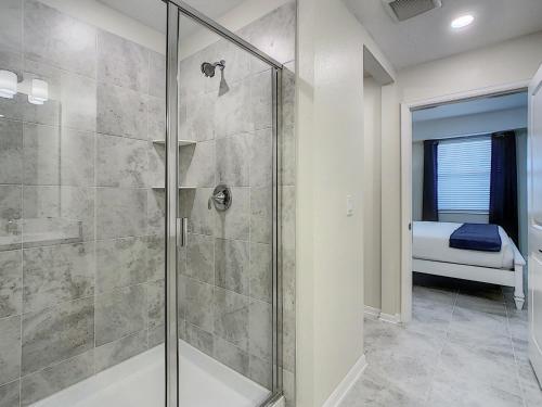 a bathroom with a glass shower with a bed in the background at Updated Condo, 5 mi to Disney, On-site Water Park in Kissimmee