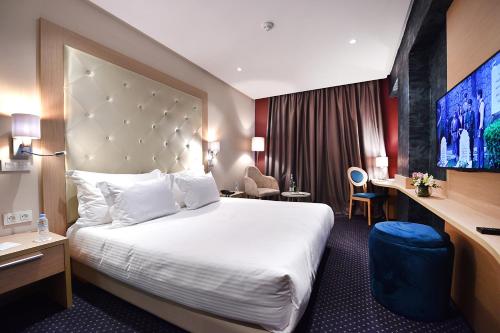 a hotel room with a large bed and a desk at Flower Town Hotel & Spa in Rabat