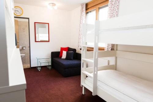 a bedroom with a bunk bed and a couch at Kurhaus Lenzerheide in Lenzerheide