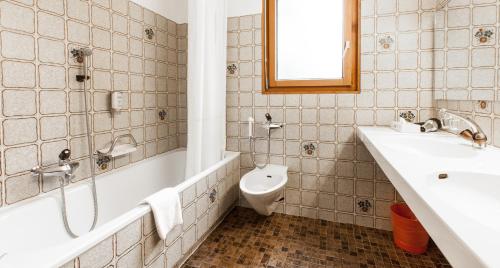 a bathroom with a tub and a toilet and a sink at Kurhaus Lenzerheide in Lenzerheide