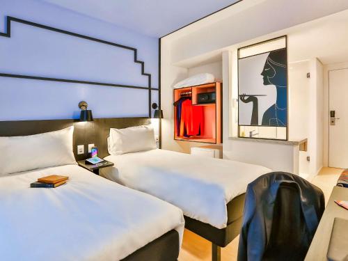 a hotel room with two beds and a mirror at ibis Styles Goiania Marista in Goiânia