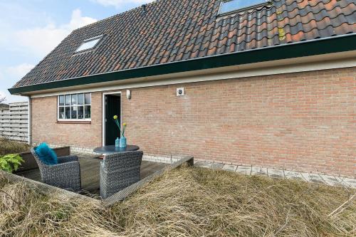 a brick house with a patio with two chairs and a table at Appartement Parkweg in Bergen aan Zee