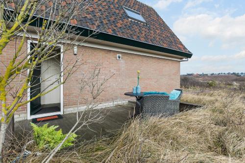 uma mesa e cadeira sentados ao lado de uma casa em Appartement Parkweg em Bergen aan Zee