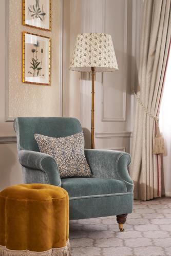 a living room with a green chair and a lamp at The Gleneagles Hotel in Auchterarder