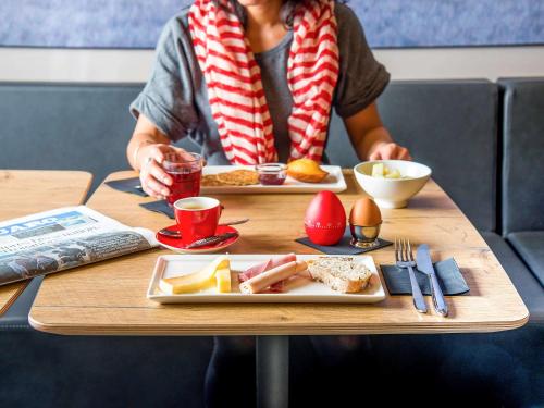 a woman sitting at a table with two plates of food at ibis Lyon Centre Perrache in Lyon