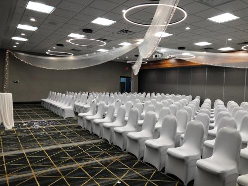 an empty room with white chairs in it at Holiday Inn & Suites St. Cloud by IHG in Saint Cloud