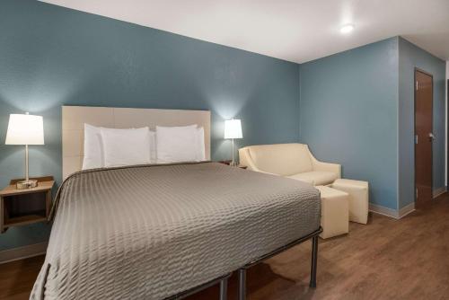a bedroom with a large bed and a chair at WoodSpring Suites Sulphur - Lake Charles in Sulphur