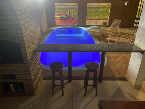 a swimming pool with two bar stools and a blue swimming pool at Pousada e Restaurante Palomar in Ilhéus