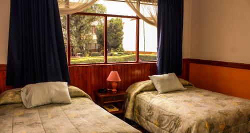 Un dormitorio con dos camas y una ventana. en Hotel Colomba, en Huaraz