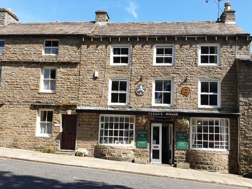 an old stone building on the side of a street at Sykes House in Askrigg