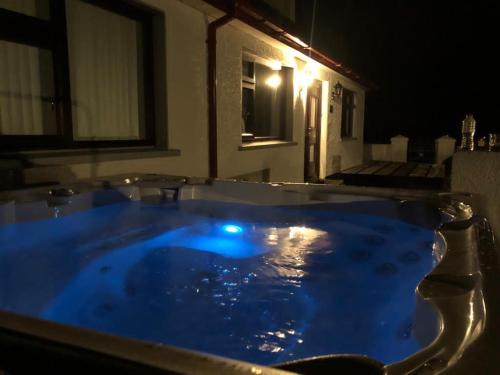 a jacuzzi tub with blue water at night at Littles Cottage, heart of the Mournes in Annalong