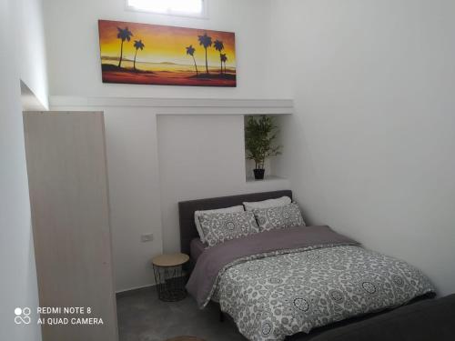 una camera da letto con un letto e un dipinto sul muro di Eilat vacation studio סטודיו נופש באילת a Eilat