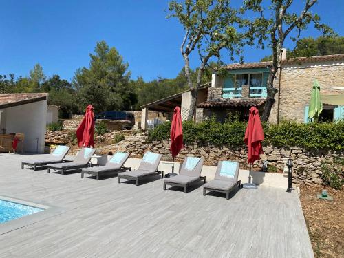 a row of lounge chairs and umbrellas next to a pool at La Bergerie des Oliviers in Méounes-lès-Montrieux
