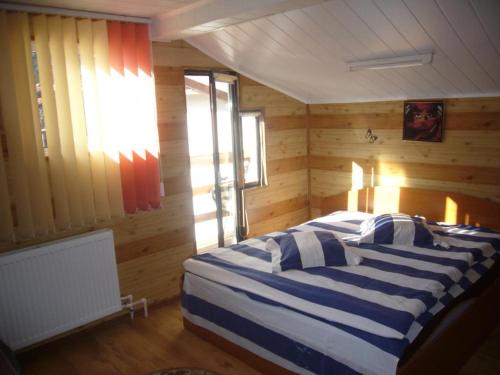 ein Schlafzimmer mit einem Bett in einem Zimmer mit Holzwänden in der Unterkunft Complex Vile Daniel in Sinaia